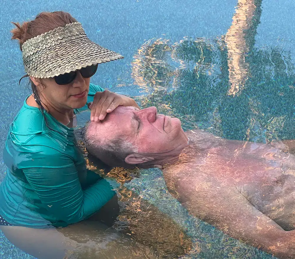 Aqua therapy instructor in the pool with patient performing craniosacral therapy